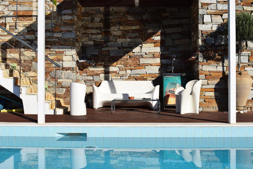a pool with white furniture next to a brick wall at Panorama Penthouse & Studios in Athens