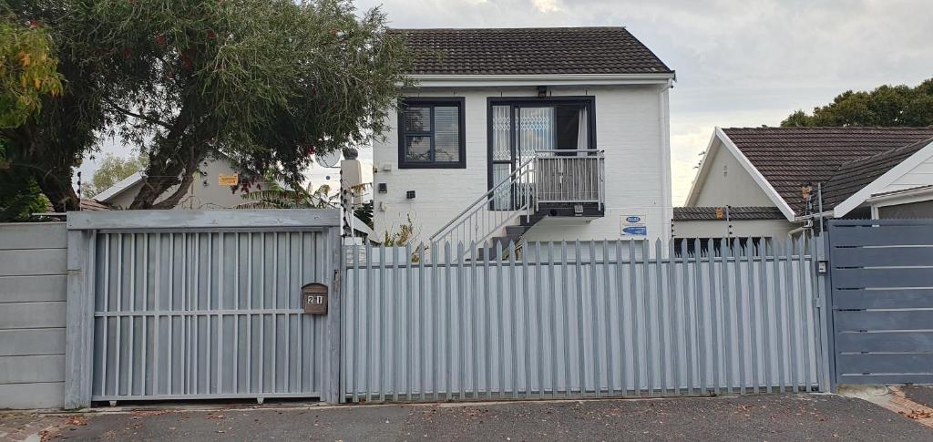 a white house with a fence and a blue gate at Quilla Quarters in Plumstead