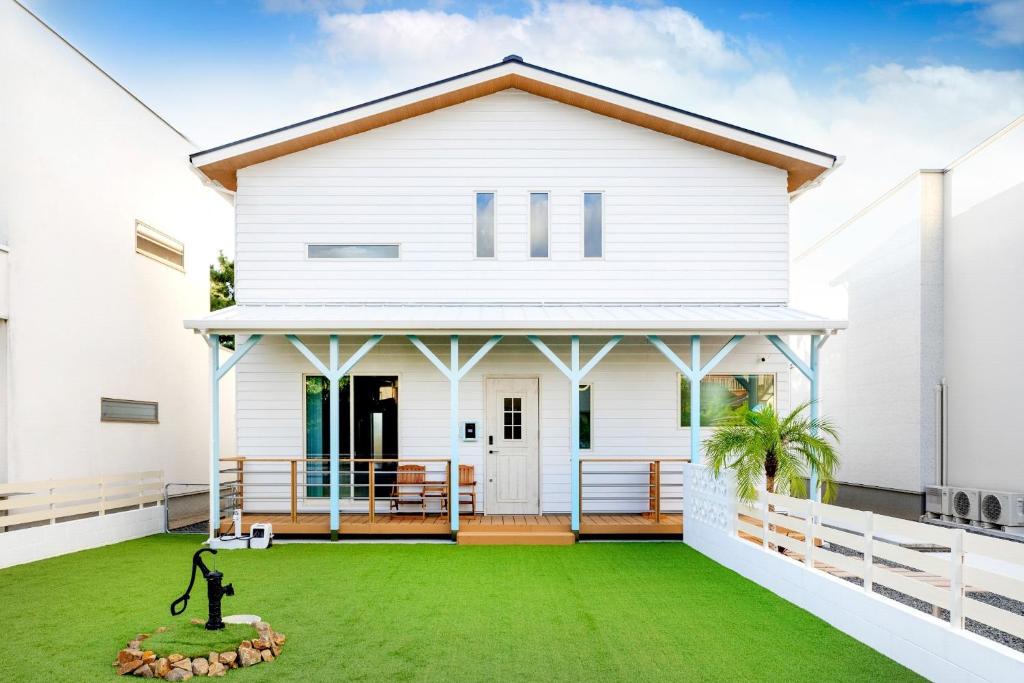 ein weißes Haus mit grünem Rasen in der Unterkunft Villa Uminosora - Vacation STAY 99789v in Karatsu