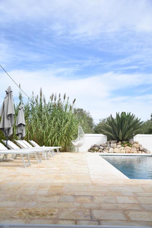 a pool with chairs and umbrellas in a resort at Oltre gli Ulivi in Ostuni