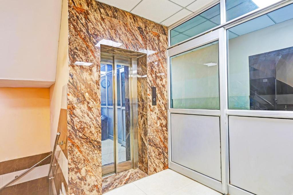 a room with a stone wall and a glass door at Hotel O Sunshine in New Delhi