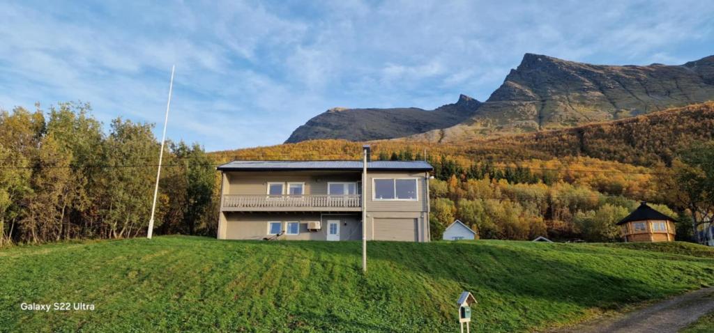a house on a hill with mountains in the background at Skogstad Ferie og fritid in Tromsø