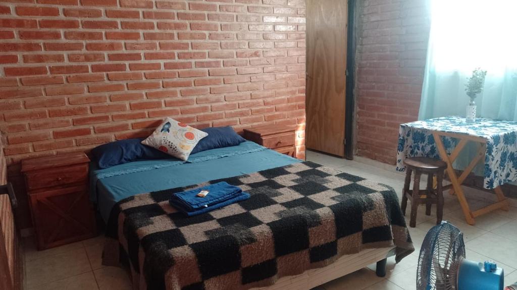 une chambre avec un lit et un mur de briques dans l'établissement Pura Vida, à Cortaderas