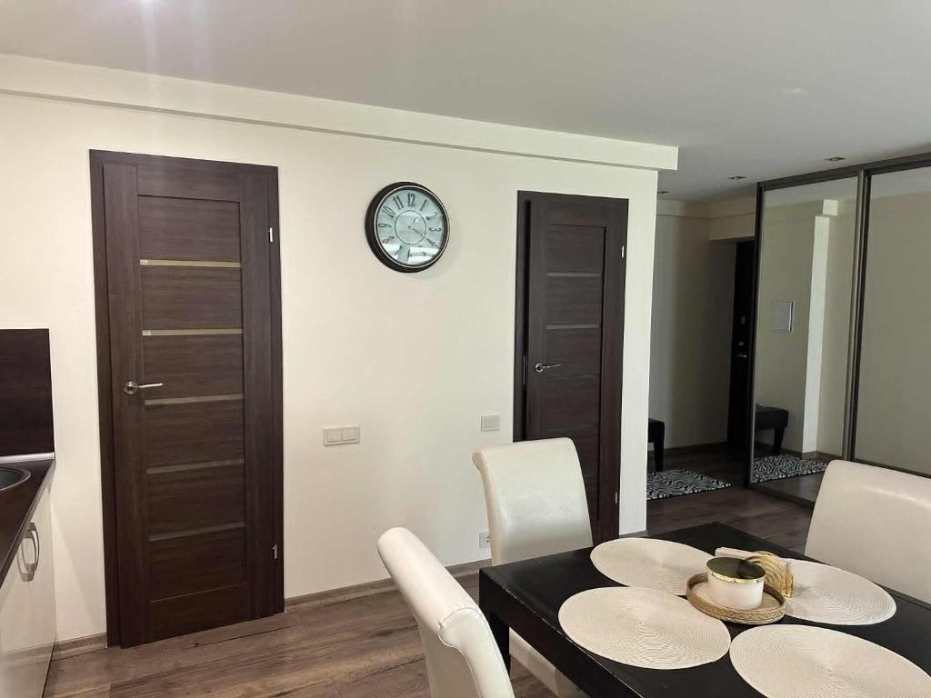 a dining room with a table and a clock on a wall at Trumpalaike buto nuoma in Panevėžys