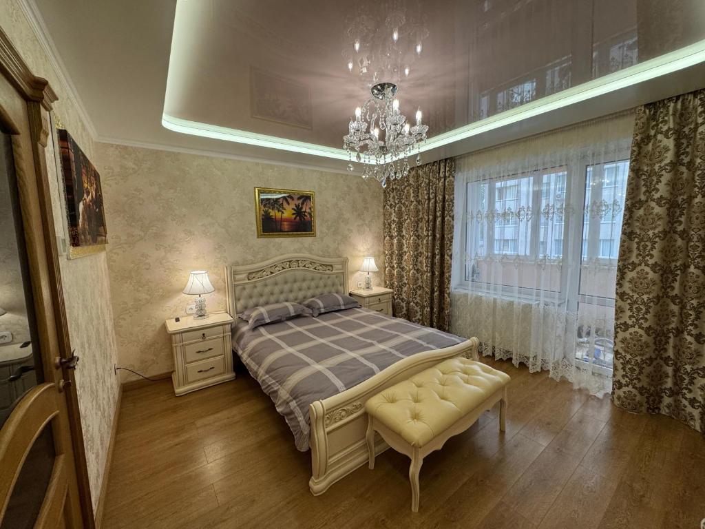 a bedroom with a bed and two tables and a chandelier at 2к люкс в класичному стилі Netflix in Khmelʼnytsʼkyy