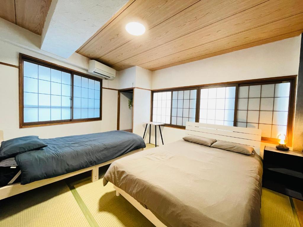 a bedroom with two beds in a room with windows at Stay Narimasu - 3rooms Apartment, 4min to Narimasu station, 1min to Donki in Tokyo