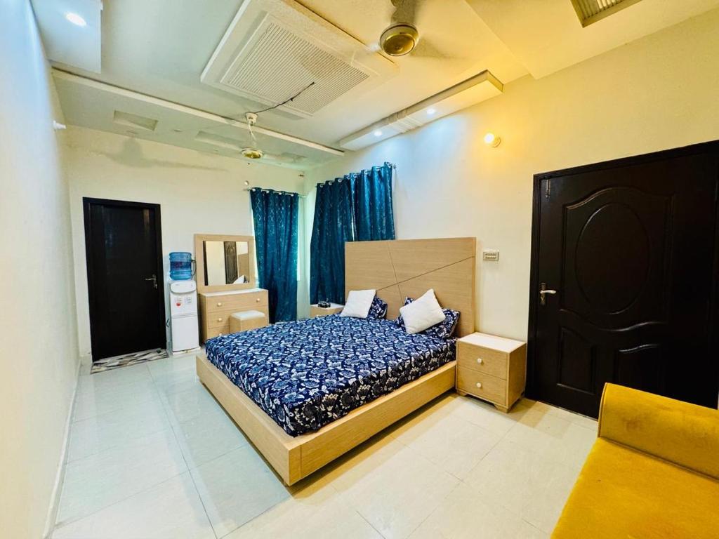 ein Schlafzimmer mit einem Bett mit blauer Bettdecke und blauen Vorhängen in der Unterkunft Multan house in Multan