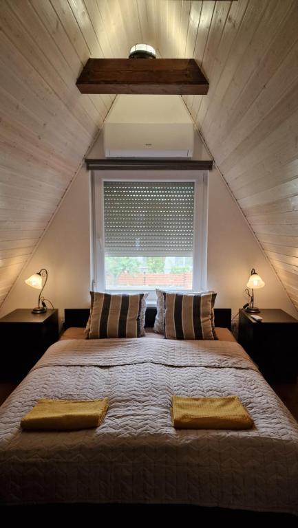 een slaapkamer met een groot bed met 2 lampen en een raam bij Velencei Odú in Velence