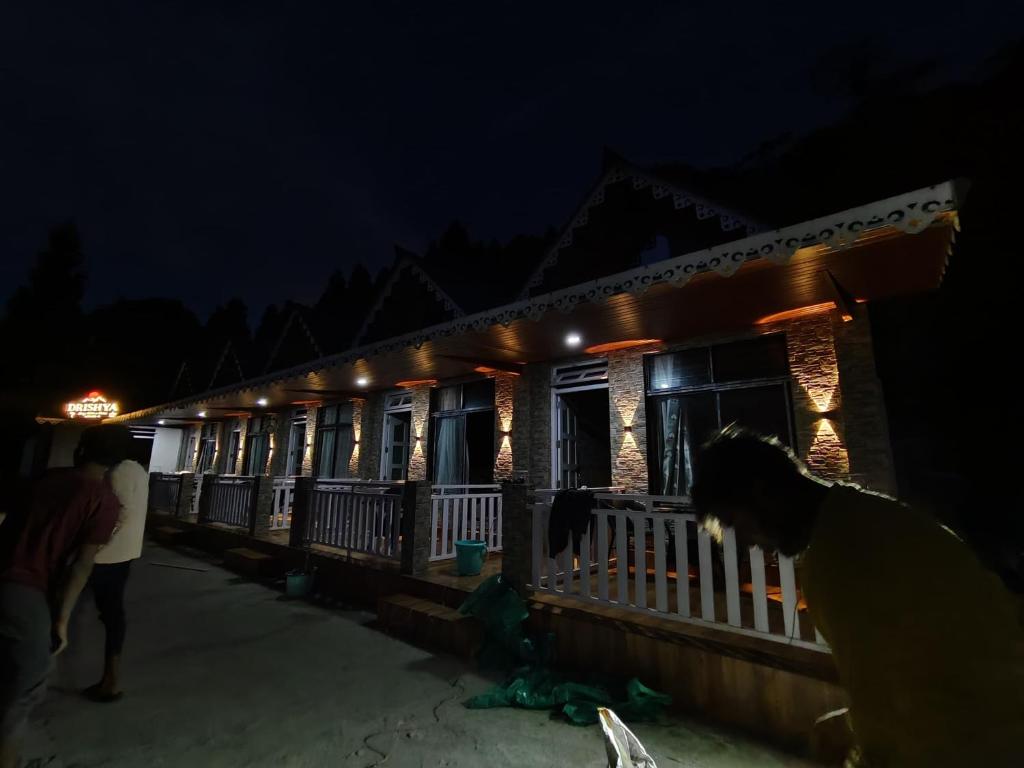 a group of people standing outside of a building at night at Drishya Stay with a view in Mangpu
