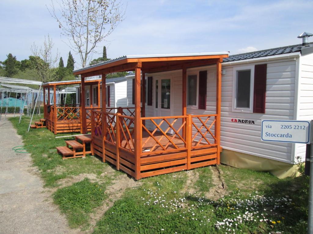 a mobile home with a porch on the grass at Mobilhome Victoria Bella Italia in Peschiera del Garda