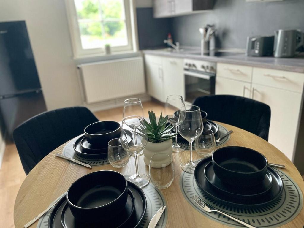 a wooden table with plates and wine glasses on it at Fundis Apartment am Schloss in Bad Harzburg