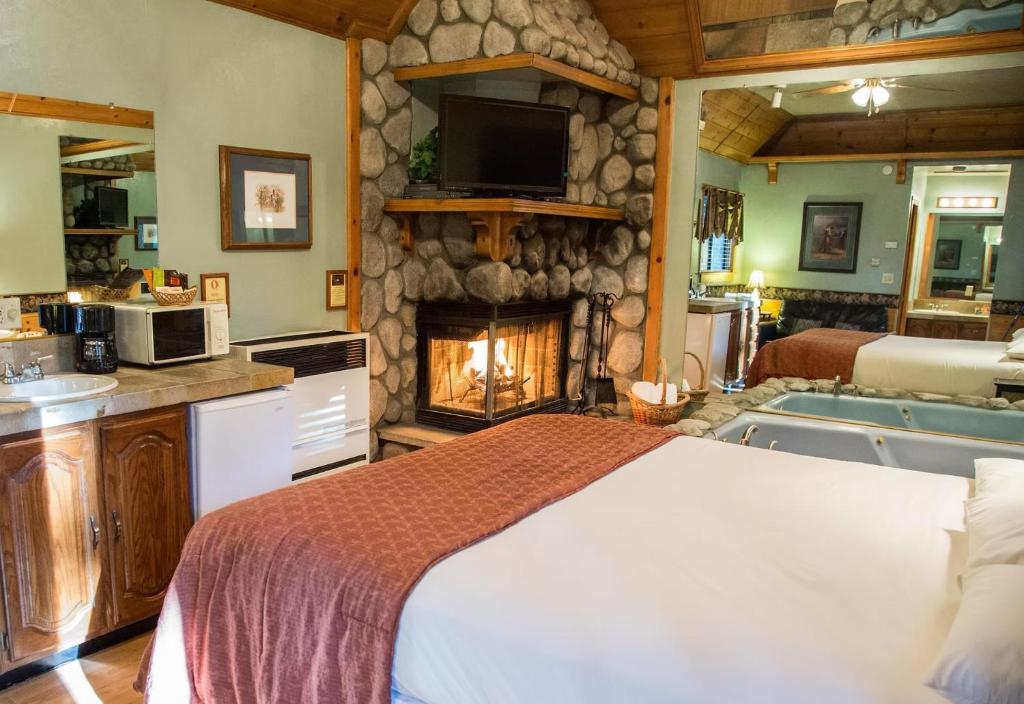 a bedroom with a large bed and a fireplace at Sleepy Forest Cottages in Big Bear Lake