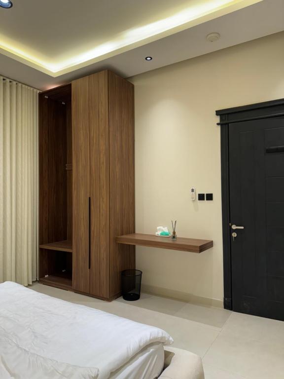 a bedroom with a bed and a wooden cabinet at Luxury 2BR - Steps To Boulevard in Riyadh