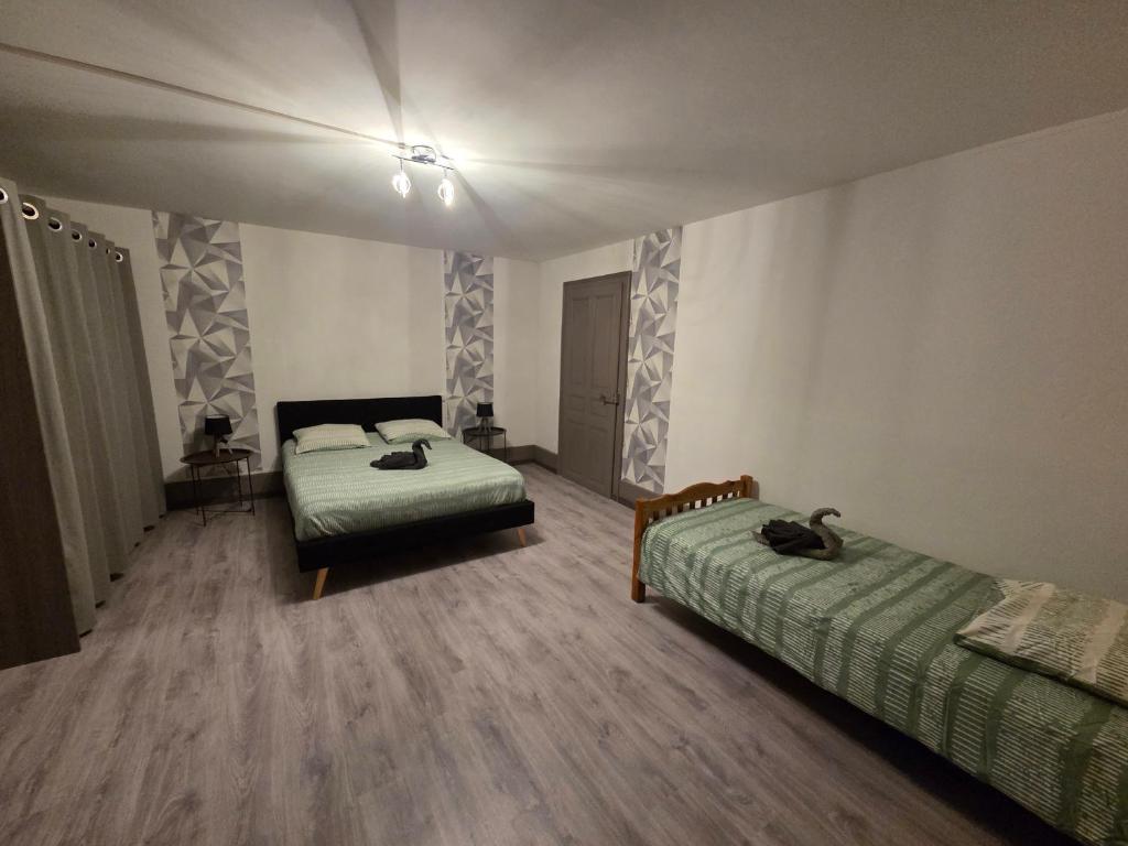 a bedroom with two beds in a room with wooden floors at Maison du bonheur in Montier-en-Der
