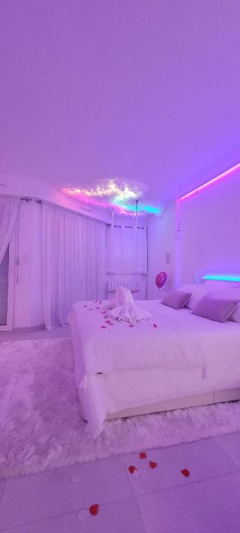 a bedroom with a large white bed with purple lights at Suite romantique avec balnéo près de Vannes - L'instant suspendu in Questembert