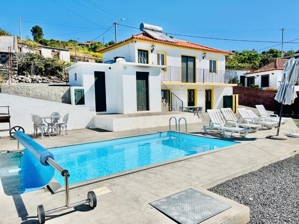 una piscina con un tobogán frente a una casa en Casa Maria Cottage with Sea View, en Estreito da Calheta