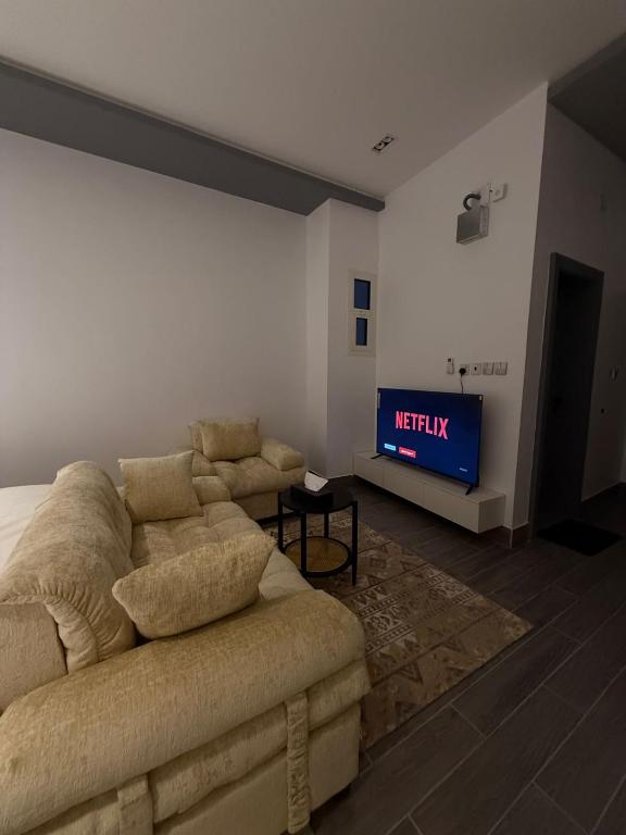 a living room with a couch and a tv at شقق النخيل المخدومة in Al Kharj