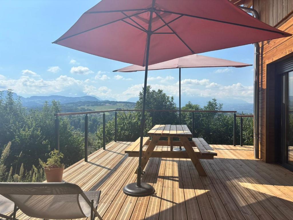 a wooden deck with a picnic table and an umbrella at Chalet vue panoramique in Fillinges