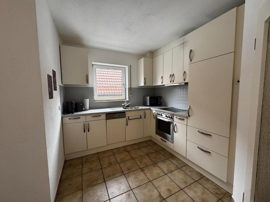 a small kitchen with white cabinets and a window at Ferien und Monteurwohnung mit Garage im Gäu in Gäufelden