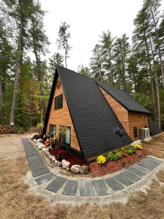 une cabane en rondins avec un toit noir et des fleurs dans l'établissement Baby Chocorua, à Tamworth
