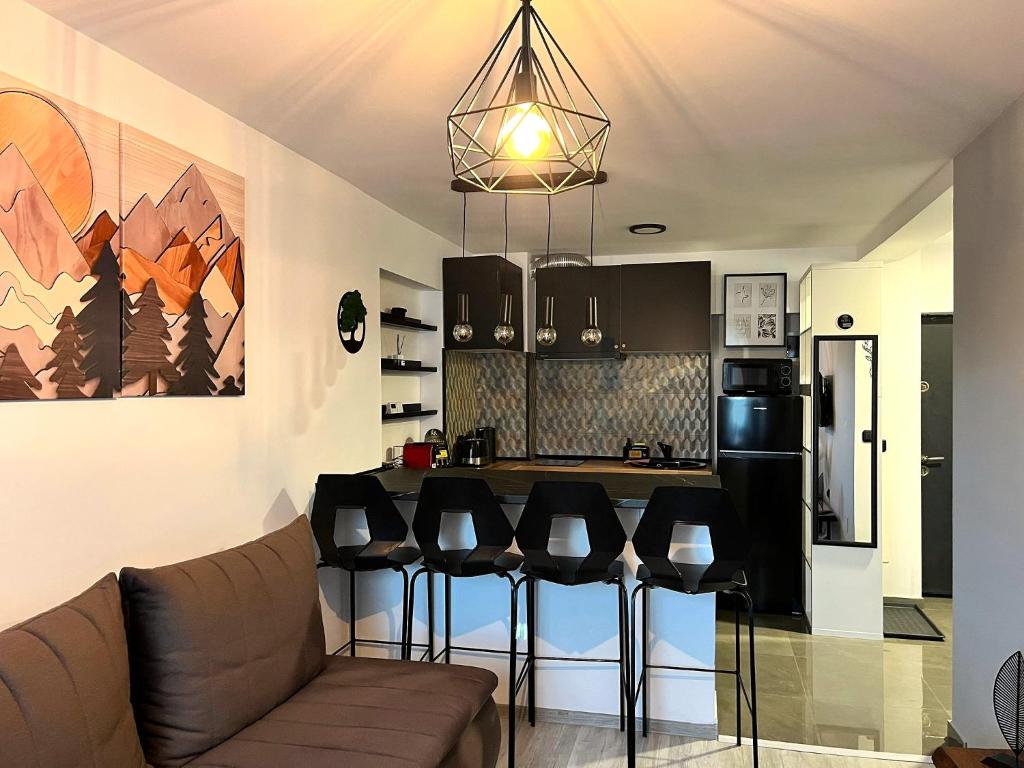 eine Küche mit einem Sofa und einer Bar mit Hockern in der Unterkunft Deer House Next to Sinaia Plaza - Balcony & Private Parking in Buşteni