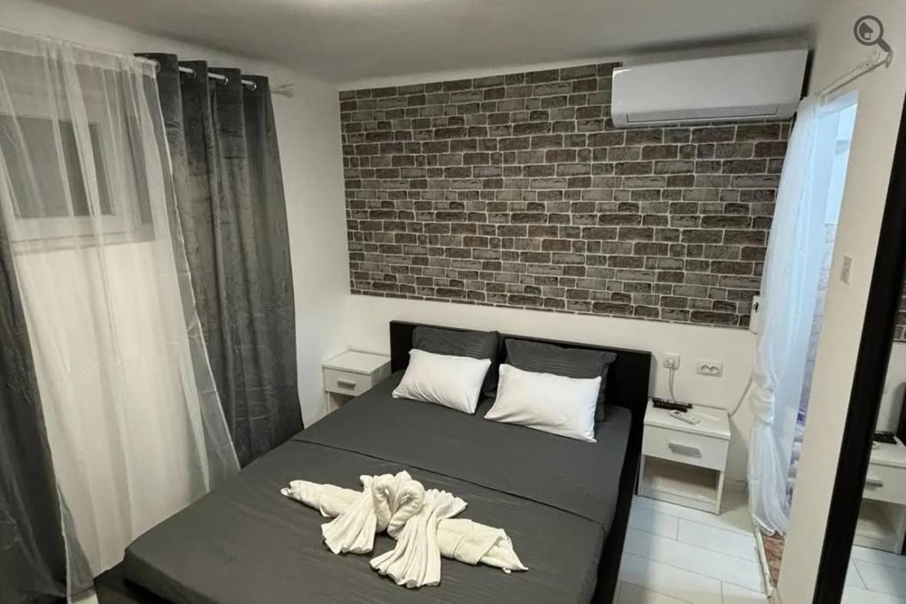 a bed in a room with a brick wall at Point apartman 1 in Belgrade