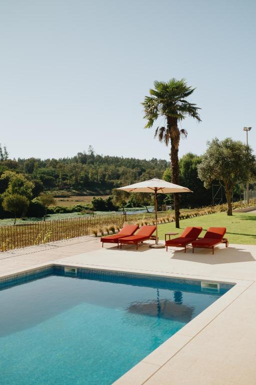 a swimming pool with two chairs and an umbrella at Casa do Ave Riverside Suite in Vila do Conde