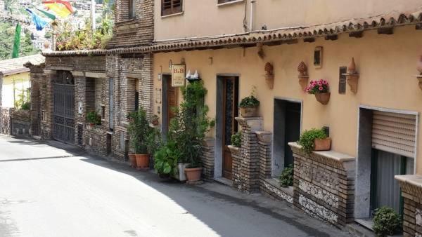 a building with potted plants on the side of a street at B&B Casa Michele in Taormina