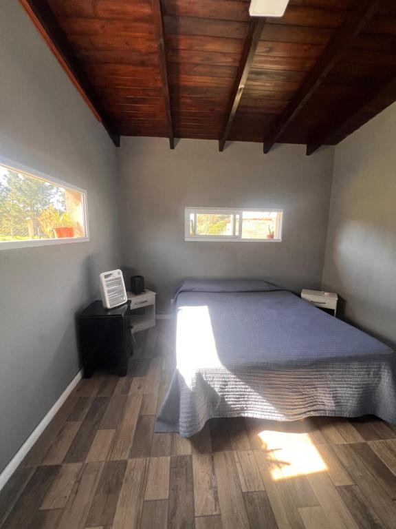 Un dormitorio con una cama grande y dos ventanas. en Casa en el parque, en Necochea