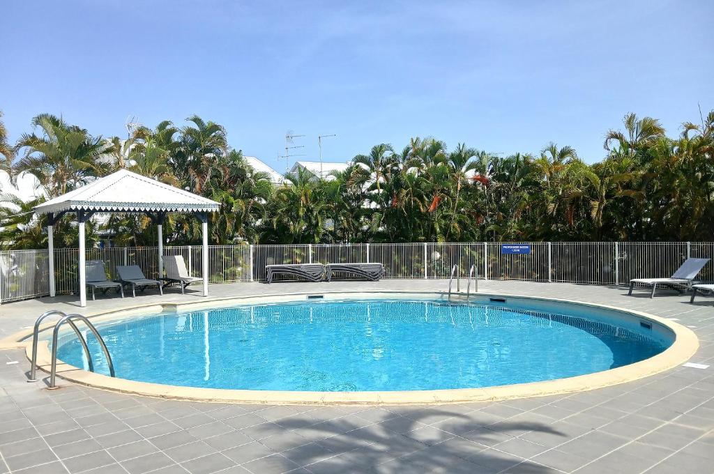 een zwembad met stoelen en een prieel bij Studio Marina Blue in Saint-François