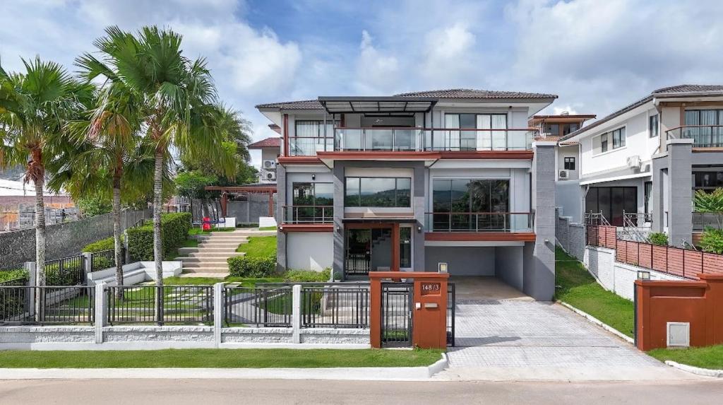 una grande casa bianca con una recinzione e palme di The Golden Palm Residence - Kathu - 10 min to Patong Beach a Ban Thung Thong