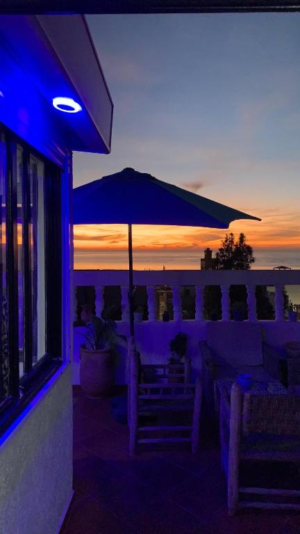 a patio with an umbrella and chairs with the sunset at Black Pearl surf yoga and skate house in Tamraght Ouzdar