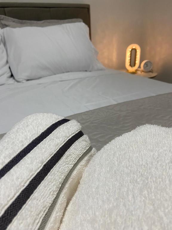 un lit blanc avec une couverture noire et blanche et une horloge dans l'établissement Lar Urbano, à Manhuaçu