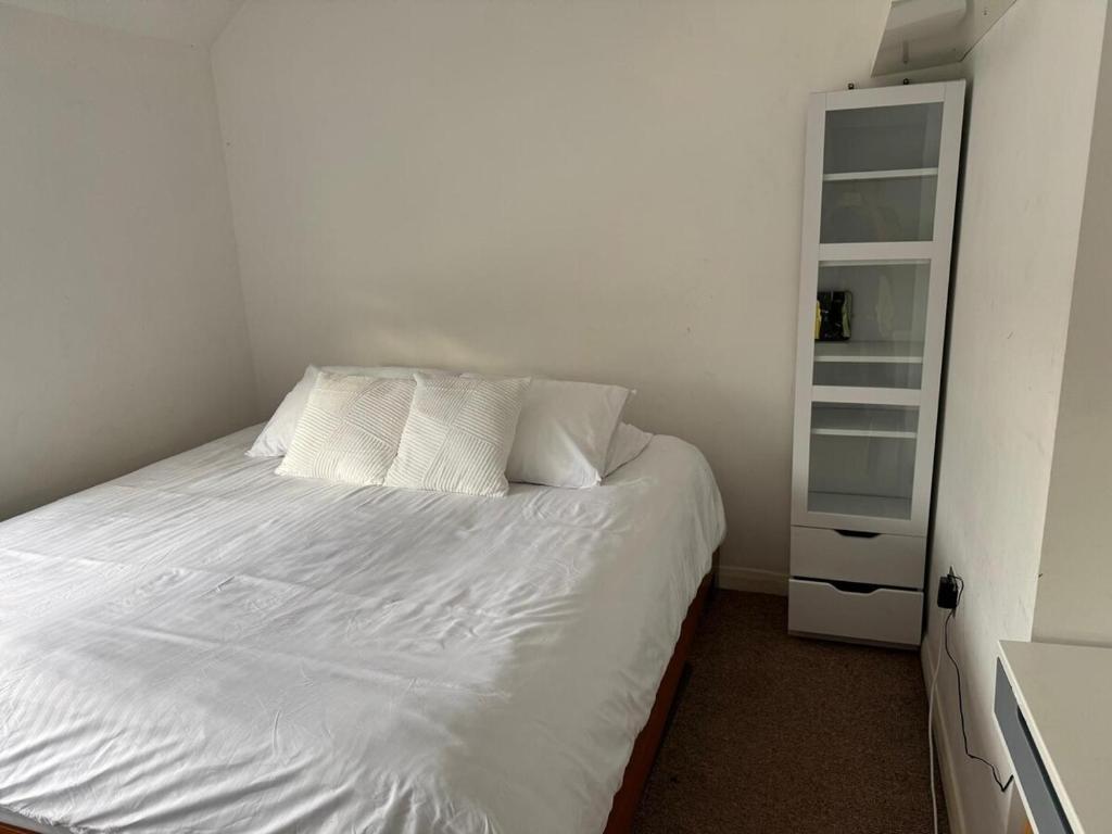 a bed with white sheets and pillows in a bedroom at 3-bedroom home with large garden and free parking in Loughton