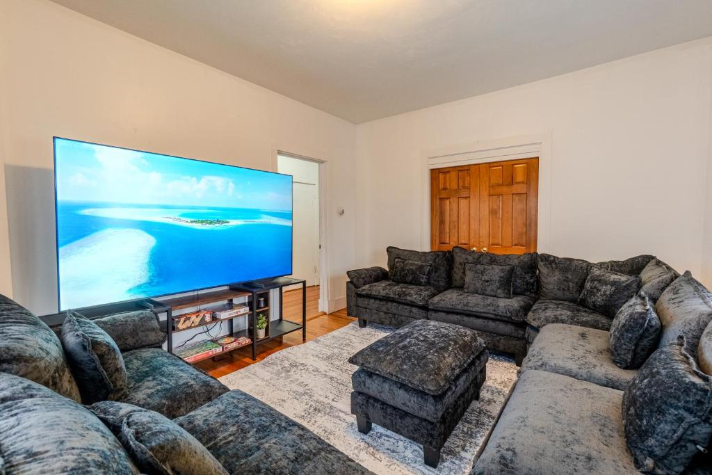 a living room with couches and a large screen tv at 4BDR|Tufts|Train|Free Parking in Winter Hill