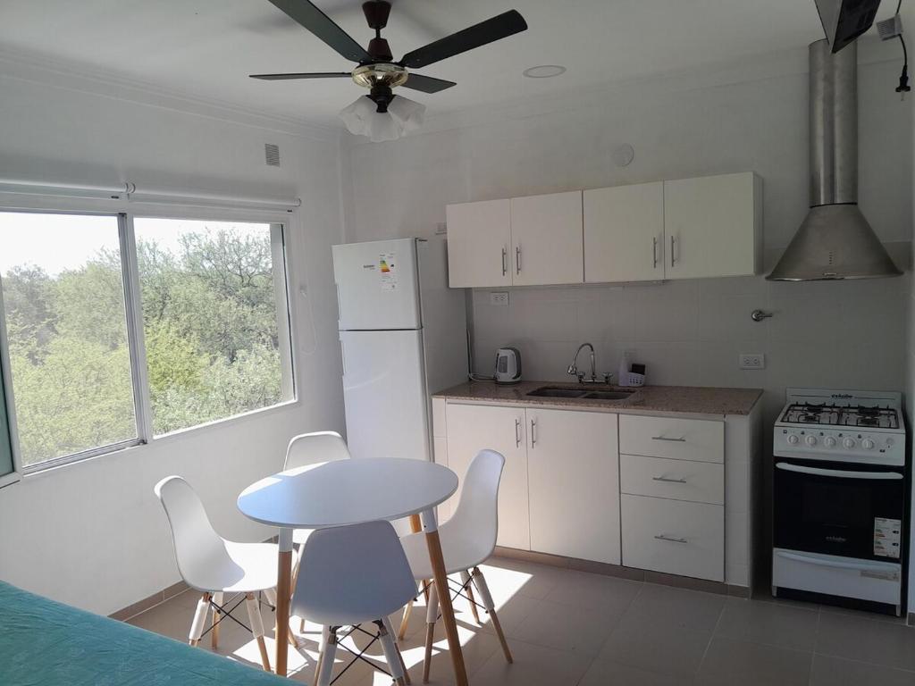 a kitchen with white cabinets and a table and chairs at Lo de guada in Los Molles