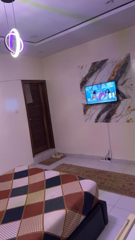 Una sala de estar con un sofá y un televisor en una pared. en chez laye, en Keur Massar