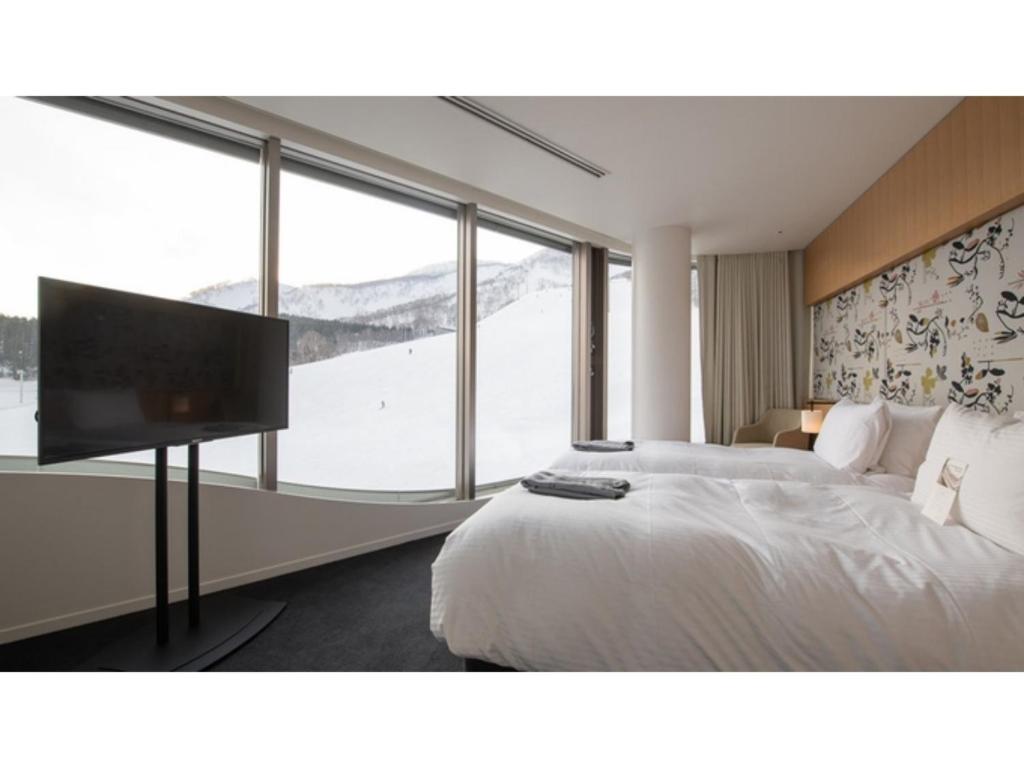a bedroom with a large bed and a flat screen tv at Skye Niseko - Vacation STAY 70563v in Niseko