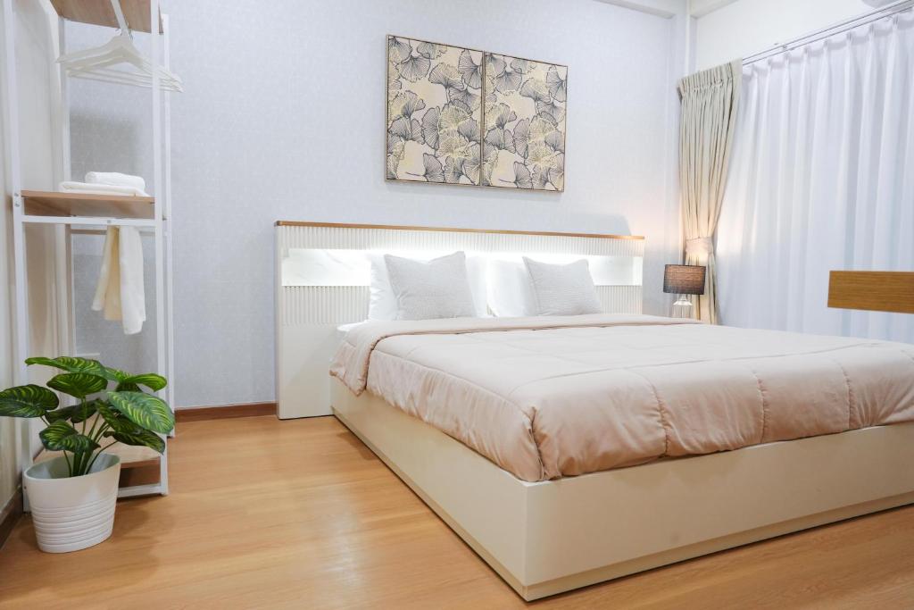 a bedroom with a white bed and a plant at Cozy KingsizeBed เจริญนคร in Ban Hua Phrong