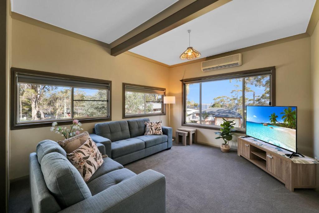 a living room with a couch and a flat screen tv at Greville on the Bay in Sanctuary Point