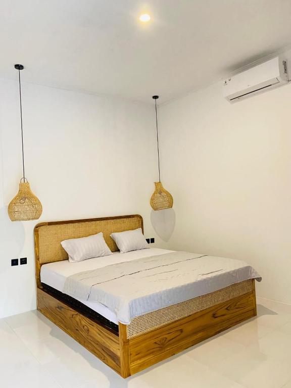 a bed in a white room with two pendant lights at PAN Homestay in Kuta Lombok