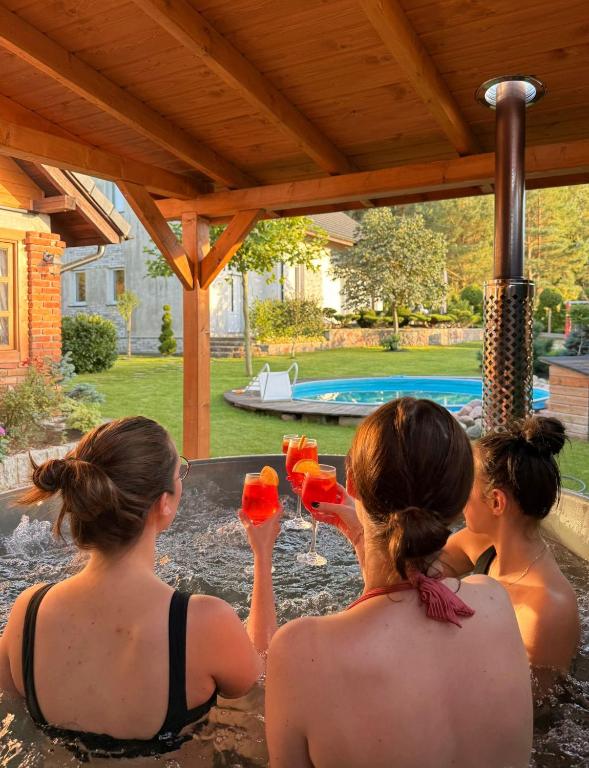 three women sitting in a hot tub with drinks at Komfortowy Dom Całoroczny - sauna, jacuzzi, bilard in Tyłowo