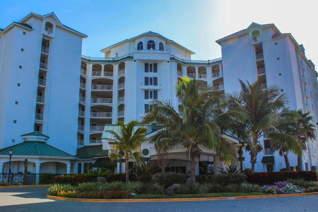 ein großes weißes Gebäude mit Palmen davor in der Unterkunft The Resort on Cocoa Beach in Cocoa Beach