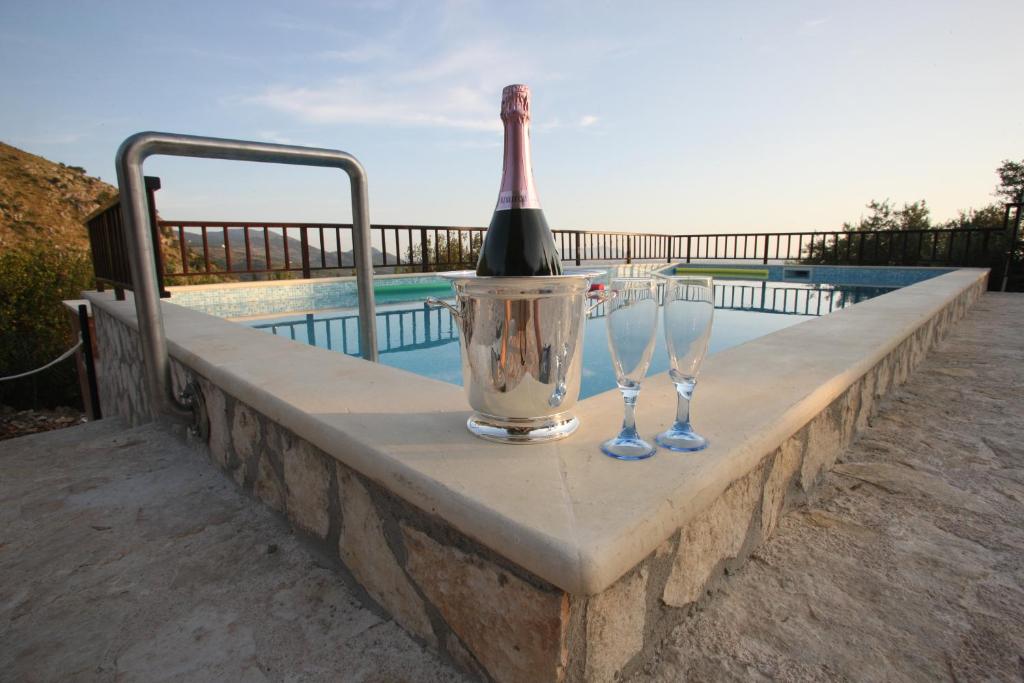 a bottle of wine and two wine glasses on a wall by a pool at Tenuta Palma in Sonnino
