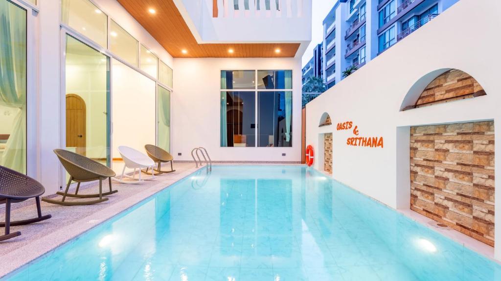 a swimming pool in a building with chairs around it at Downtown Oasis 芭提雅市中心独栋泳池别墅 A 5卧6卫 KTV BBQ 芭提雅海滩步行街500m in Pattaya South