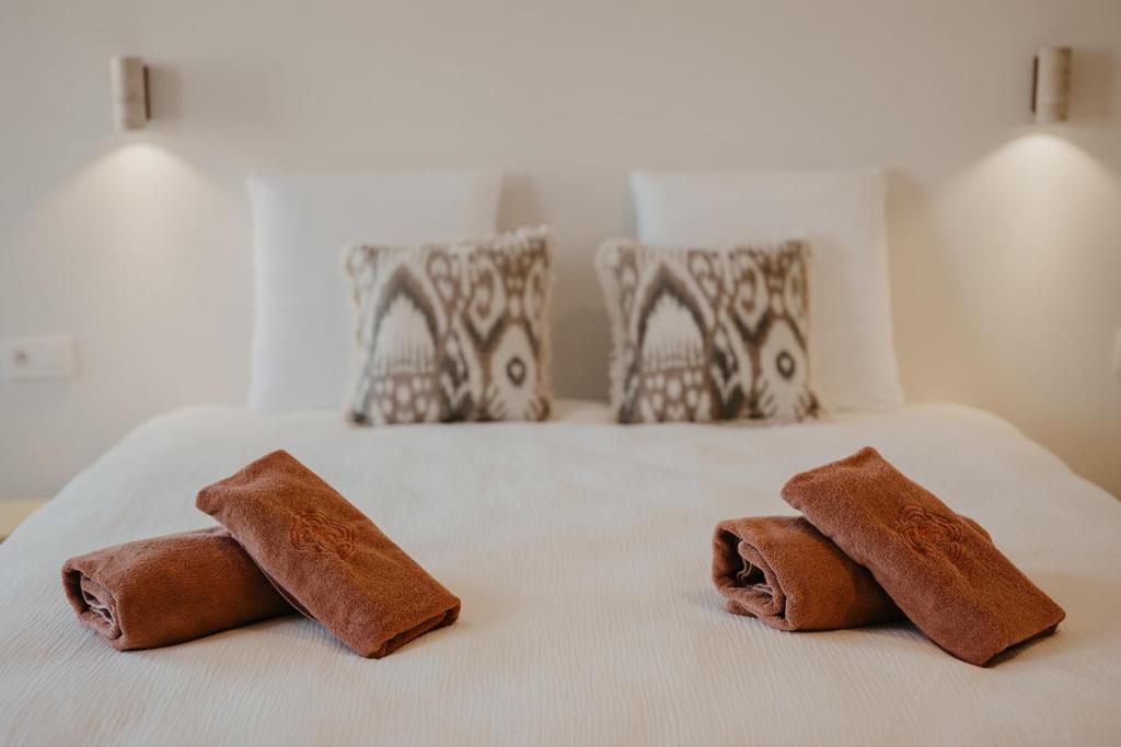 deux serviettes marron sur un lit blanc avec des oreillers dans l'établissement Isidore, à Bruges