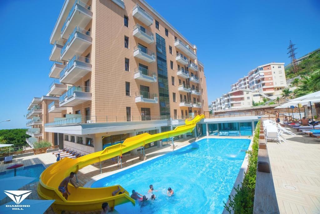 une piscine avec toboggan en face d'un bâtiment dans l'établissement Diamond Hill Resort & SPA, à Vlorë