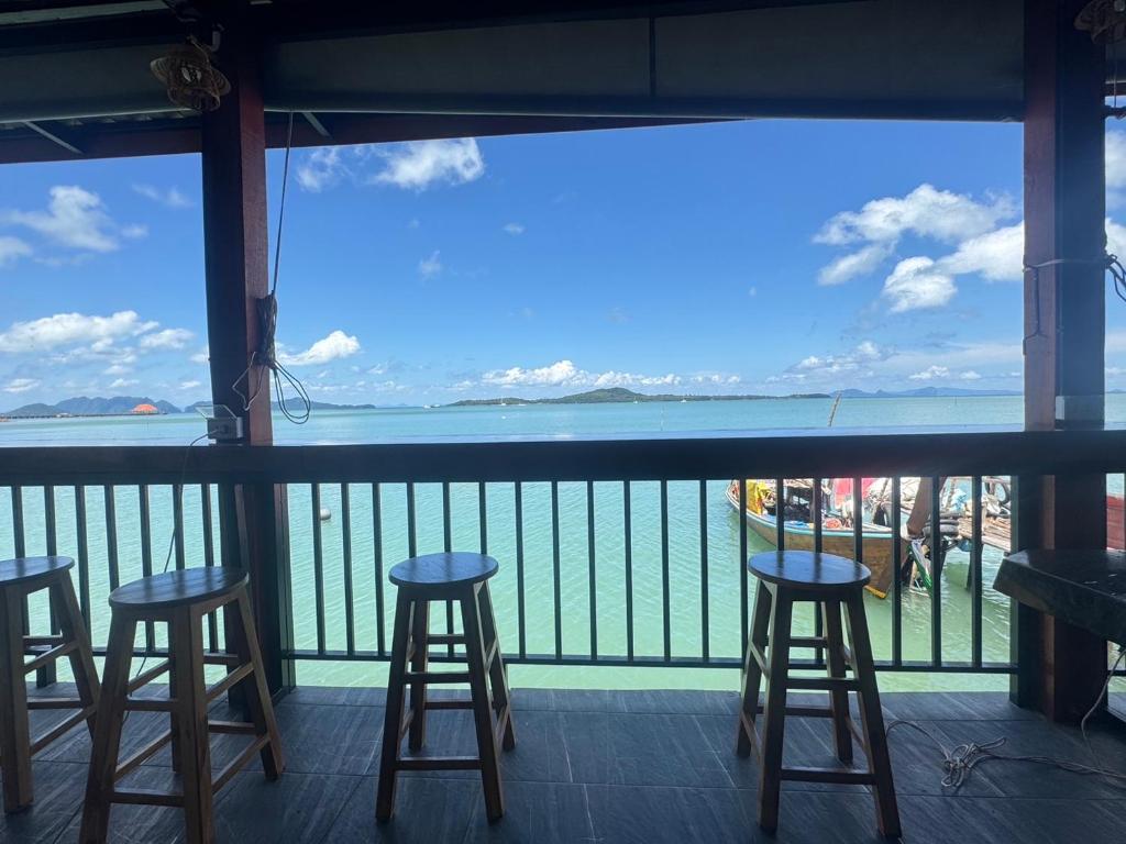 a balcony with stools and a view of the ocean at Sunrise House at Lanta in Ban Nong Chaeng