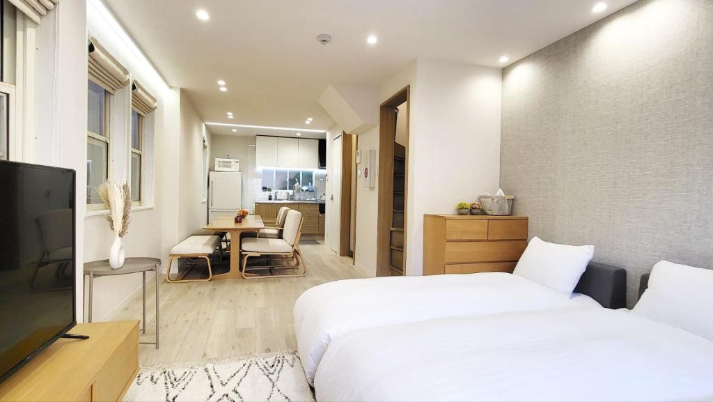 ein Schlafzimmer mit zwei Betten und einem Tisch und eine Küche in der Unterkunft STAY ARI Higashishinjuku in Tokio