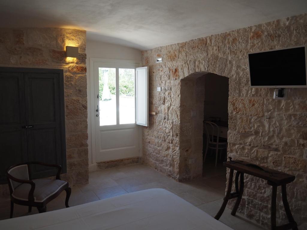 - un salon avec une télévision sur un mur en pierre dans l'établissement Masseria Gravinella, à Fasano